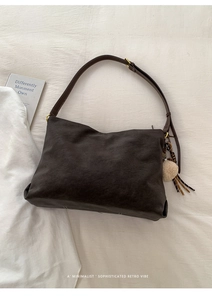 Close-up of retro matte dark brown tote bag with fuzzy pom-pom and fringe keychain