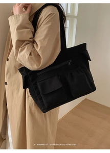 Detail of black corduroy tote bag showing front zip pocket and cargo flip pockets