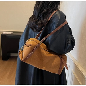 Detail view of a vintage brown cylindrical bag featuring adjustable leather eyelet strap