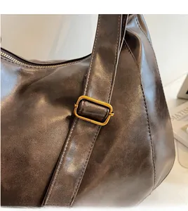 Detail of adjustable long shoulder strap with gold metal buckle on brown tote bag