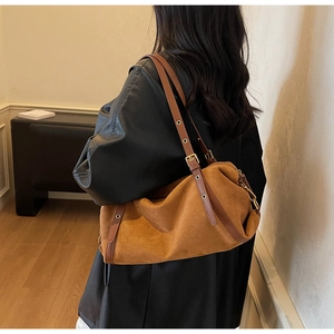 Brown frosted suede underarm bag with vintage metal eyelets and adjustable strap worn by model