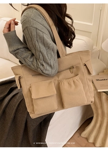 Detailed texture of beige corduroy tote bag showing multi-pocket design and strap