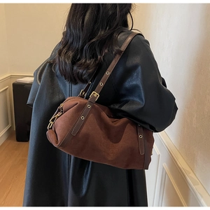 Brown suede baguette bag with adjustable strap and metal hardware on a model's shoulder