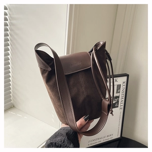 Detail of brown suede bucket bag featuring leather flap and brand logo embossing