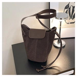Detail of suede bucket bag with embossed logo and leather drawstring closure