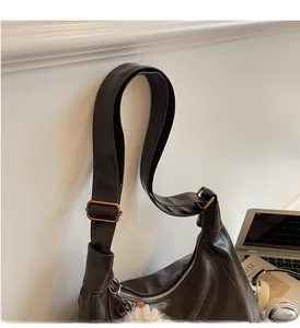 Detail of dark brown leather hobo bag with adjustable strap and plush charm accent