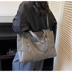Vista posteriore dettagliata di una borsa tote grigia con angoli intrecciati e rivetti