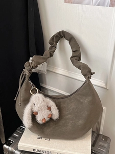 Olive brown leather hobo bag with scrunchie strap and plush bunny charm on books