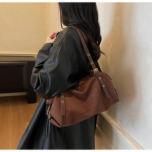 Close-up of matte dark brown suede shoulder bag with golden hardware and eyelet strap