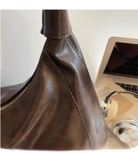 Detail of dark brown leather hobo bag with precision stitching and metal zipper