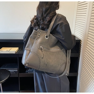 Detail of grey tote bag showing unique woven corner stitching and metallic rivet accents