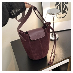 Detail showing Burgundy suede bucket bag with embossed logo and premium leather strap