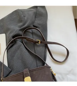 Detail of dark brown matte shoulder bag with golden stripe buckle and adjustable strap