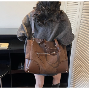 Dettaglio di una grande borsa tote marrone con cuciture intrecciate e tasca con zip