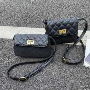 Détail de deux sacs à rabat matelassés noirs en deux tailles sur un fond d'asphalte extérieur