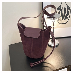 Detailed close-up of dark wine red bucket bag showing suede texture and embossed logo