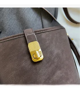 Detailed macro view of dark brown pebbled leather texture and elegant gold metal clasp