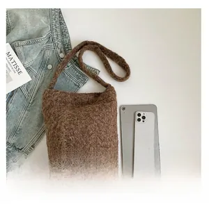 Détail d'un sac cabas en peluche marron avec texture de laine bouclée sur fond blanc