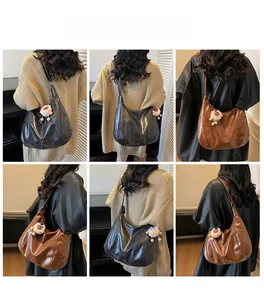 Detail view of large capacity glossy leather hobo bag with cute sheep charm in black and brown