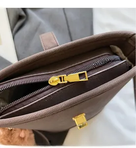 Close-up of brown litchi grain leather bag with smooth gold zipper and metallic lock