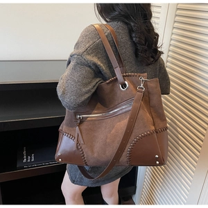 Detail of a large brown tote bag showing suede and leather patchwork with woven edges