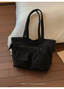 Detail of black corduroy tote bag showing multiple functional pockets and soft ribbed texture