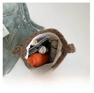 Vue intérieure montrant la grande capacité du sac fourre-tout en peluche marron avec objets