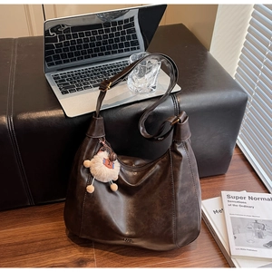 Detail of soft brown faux leather tote bag with a white plush lamb keychain on its side