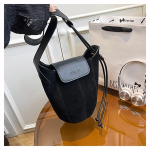 Detail of black frosted suede bucket bag featuring leather flap and embossed logo
