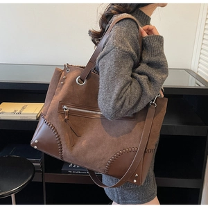 Detail view of brown large tote bag with hand-stitched seams and metal rivet accents