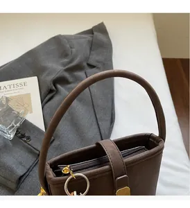 Detail of a brown bucket bag showing sturdy top handles and smooth matte leather texture