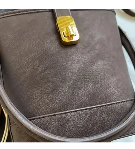 Close-up of the vintage brown leather bucket bag featuring a gold rectangular twist lock