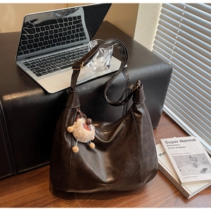 Detail of dark brown soft faux leather tote bag with wide strap and plush bear charm