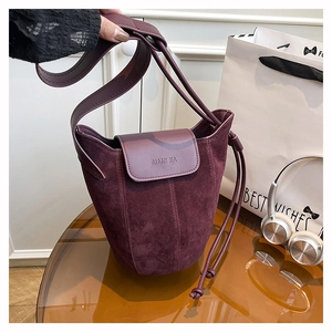 Detail of burgundy frosted suede bucket bag showing embossed logo and leather texture