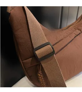Detail view of the smooth adjustable woven shoulder strap on this brown crossbody bag