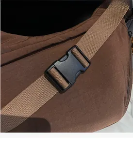 Detail of durable black plastic buckle and woven strap on brown canvas shoulder bag