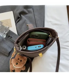 Top view of deep brown bucket bag showing large interior capacity with a plush dog charm