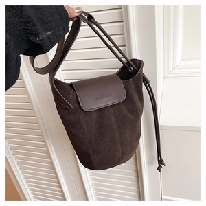 Detail of dark brown matte suede bucket bag with leather flap and embossed minimalist logo