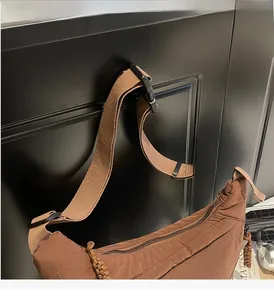 Close-up of brown nylon dumpling bag with adjustable fabric strap and plastic buckle detail
