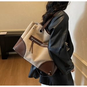 Detail of vintage canvas tote with brown leather corners and metal zipper pocket