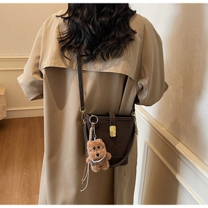 Sac seau marron foncé avec fermoir doré et pendentif ours porté à l'épaule