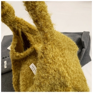 Detail of soft yellow faux fur fabric texture and brand label on a plush tote bag