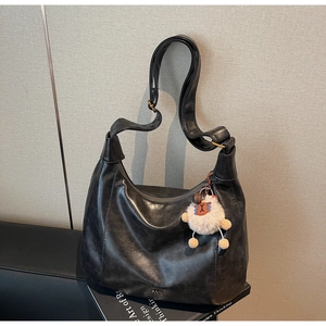 Detail of vintage black hobo bag with matte leather texture and cute sheep charm