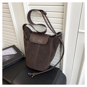 Detail of dark brown suede bucket bag with stitched leather trim and embossed logo
