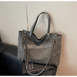 Detail of dark grey tote bag with suede texture, stitching accents and silver metal studs
