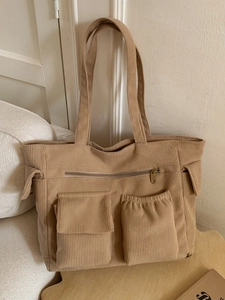 Minimalist khaki corduroy tote bag with multiple pockets shown in a cozy home setting