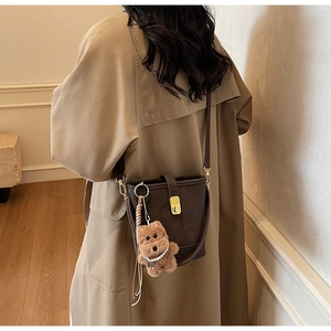 Détail d'un sac seau marron vintage avec fermoir doré et accessoire d'ours en peluche