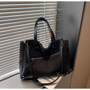 Detailed view of black tote bag with suede splicing and metal rivet protection on corners