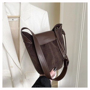 Close-up of AIAMI JIA matte suede bucket bag with embossed logo and premium textures