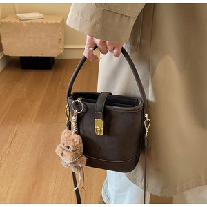 Détail du sac seau vintage marron foncé avec fermoir doré et charme d'ours en peluche